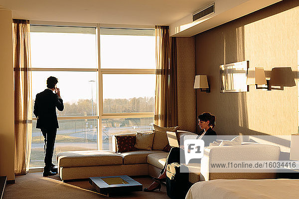Businessman and businesswoman working in hotel bedroom