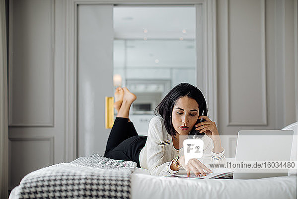 Geschäftsfrau benutzt Smartphone und Laptop in einer Suite