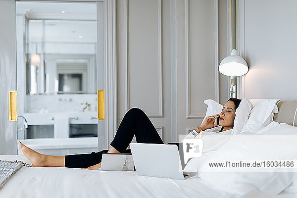 Geschäftsfrau benutzt Smartphone und Laptop in einer Suite