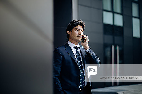 Businessman using smartphone in front of office building