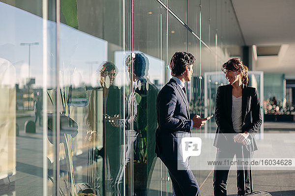 Businessman and businesswoman talking outside glass building  Malpensa  Milan