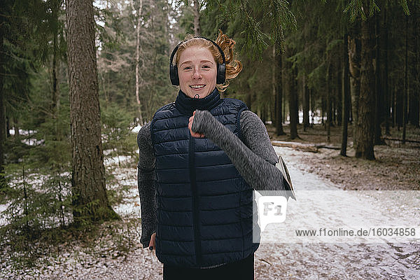 Porträt einer selbstbewussten Frau beim Laufen in verschneiten Wäldern