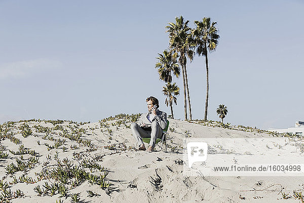 Geschäftsmann spricht mit einem Smartphone am sonnigen Strand  Los Angeles  Kalifornien