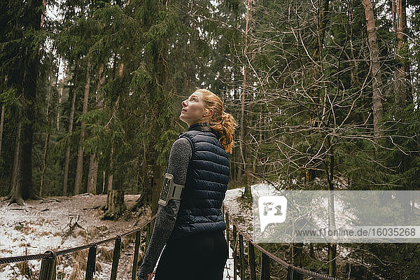 Neugierige Läuferin auf Steg in verschneiten Wäldern