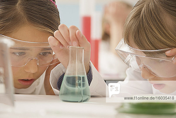 Neugierige Schülerinnen der Junior High School untersuchen Flüssigkeit im Wissenschaftsbecher