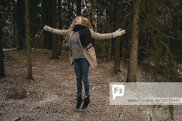 Unbekümmerte Frau springt vor Freude im Wald