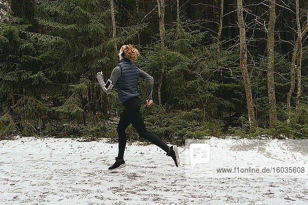 Woman running in snowy woods