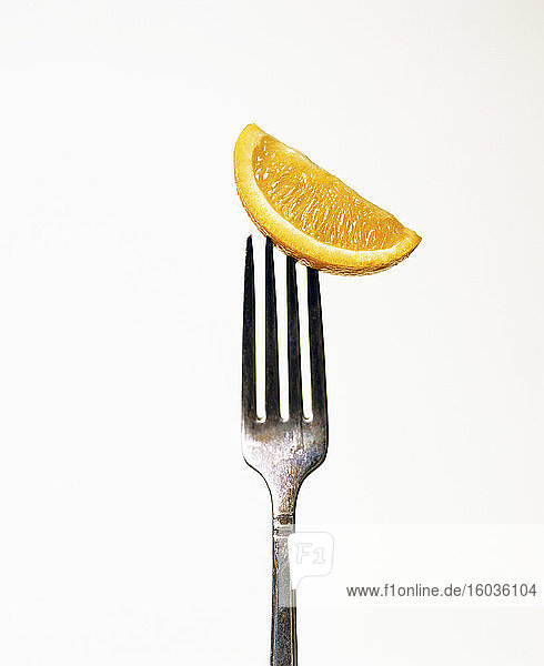 Eine Orangenspalte aufgespießt auf einer Gabel