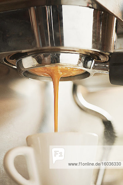 Espresso fliesst aus Espressomaschine in Tasse