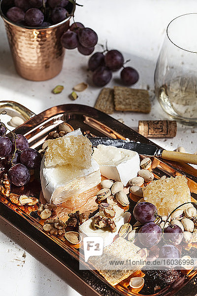 Käseplatte mit Brie  Honigwabe  Crackern  Walnüssen  Pistazien  Trauben und Weißwein
