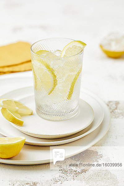 Ein Glas Wasser mit Eiswürfeln und Zitronenscheiben