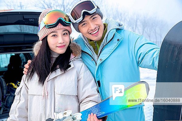 Glückliche junge Paare mit Skiern umarmen sich