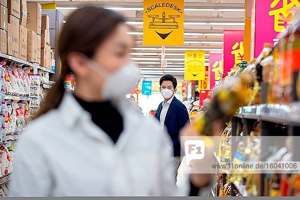 Das junge Paar  das beim Einkaufen im Supermarkt eine Maske trägt