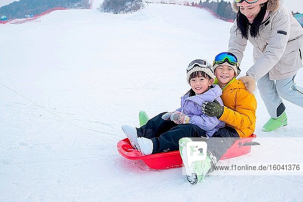 Ski resorts on the mother pushed the children sitting in the snow slide