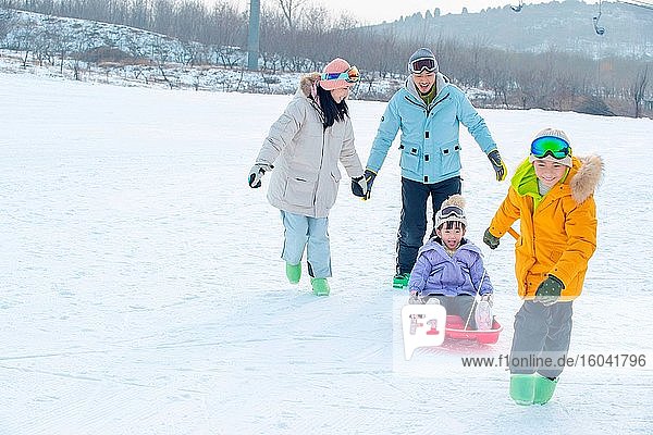 Happy family of four play snow skateboard