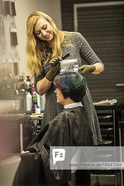Hairdresser in a hairdressing salon dying strands of hair with aluminium foil  North Rhine-Westphalia  Germany  Europe