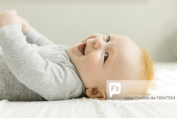 Smiling baby boy lying on bed