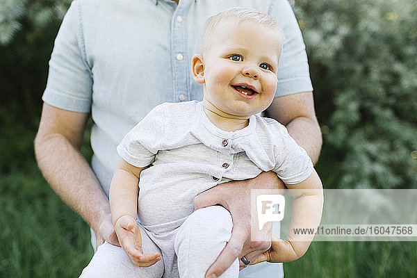 Freiluftporträt eines kleinen Jungen  der von seinem Vater im Freien getragen wird