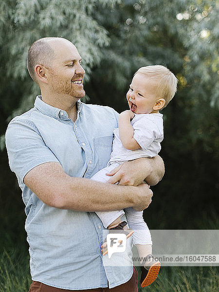 Outdoor portrait of father carrying baby son