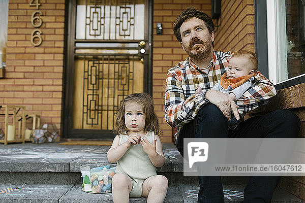 Vater mit Kindern auf der Veranda sitzend