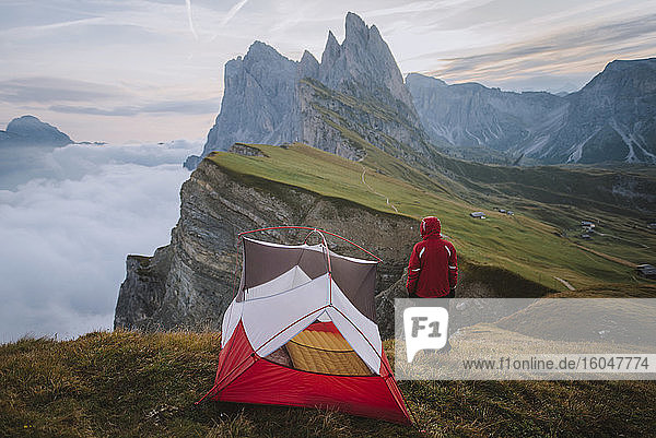 Italien  Dolomiten  Seceda-Berg  Mann steht beim Zelt und schaut auf den Seceda-Berg in den Dolomiten