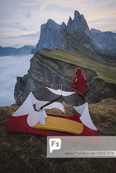Italy  Dolomite Alps  Seceda mountain  Man standing near tent looking at scenic view of Seceda mountain in Dolomites