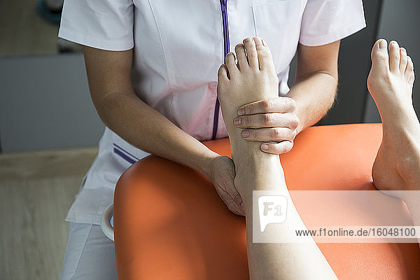 Die Hände einer Physiotherapeutin massieren den Fuß einer Frau