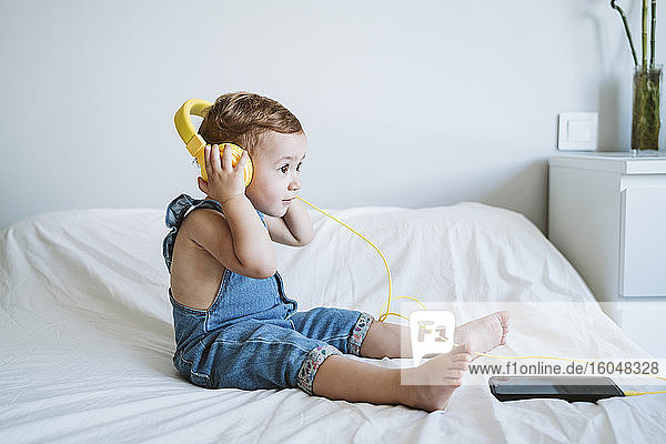 Baby girl at home listening to music on bed