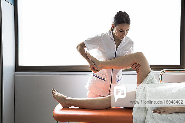 Physiotherapeutin behandelt das Bein einer Patientin