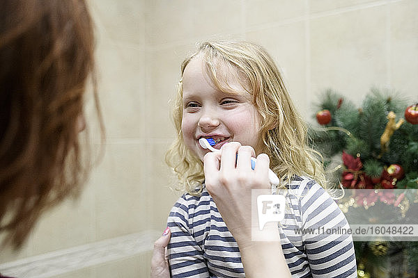 Ausgeschnittenes Bild einer Frau  die ihrer Tochter beim Zähneputzen zu Hause hilft