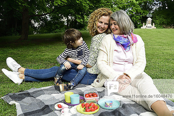 Glücklicher Junge genießt Picknick mit Mutter und Großmutter im öffentlichen Park