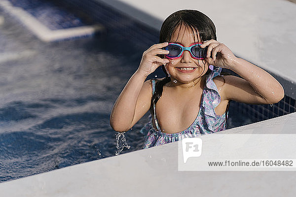 Portrait of grinning little girl with swimmming goggles in pool
