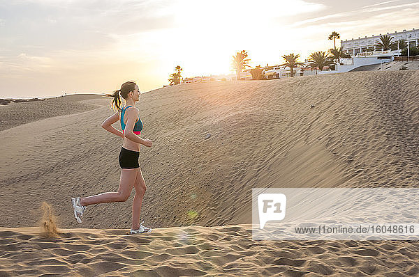 Frau  die bei Sonnenaufgang durch die Dünen läuft  Gran Canaria  Spanien