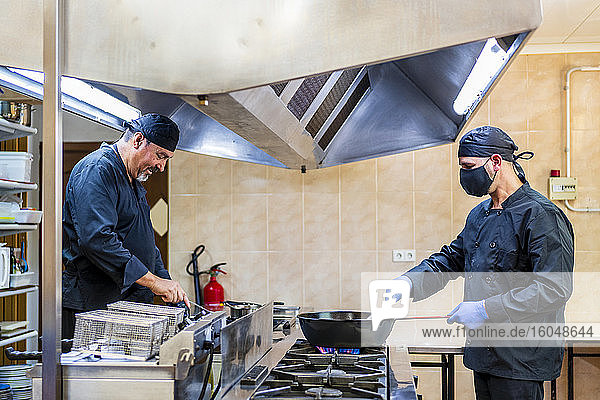Traditional cooking in restaurant kitchen  chef wearing protective mask