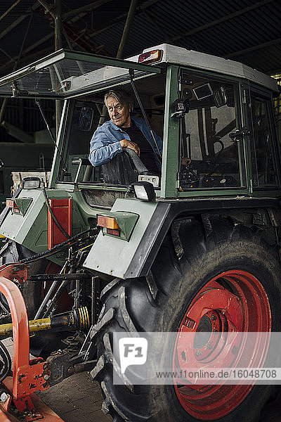 Älterer Mann fährt Traktor auf einem Bauernhof