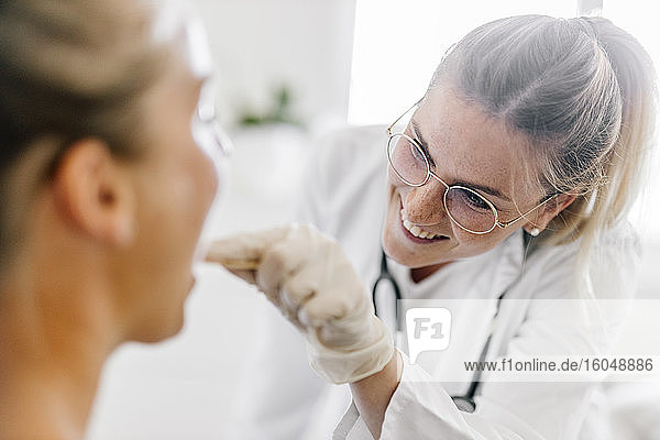 Ärztin  die eine Patientin mit Zungenspatel untersucht