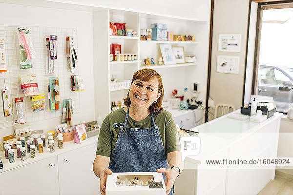 Lächelnde Bäckerin  die im Laden stehend eine Cupcake-Box ausliefert