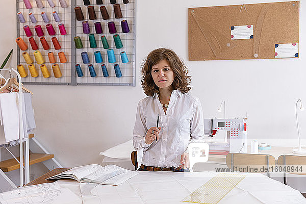 Female fashion designer standing at workbench in studio