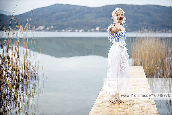 Porträt einer modischen blonden Frau auf einem Steg am Wörthersee  Österreich