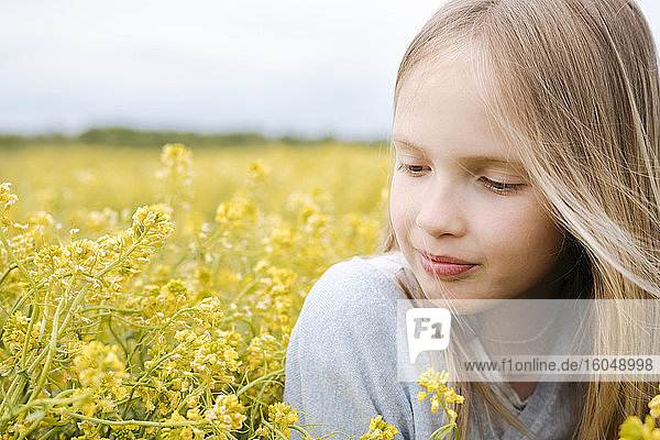 Portrait of girl looking at rape flowers