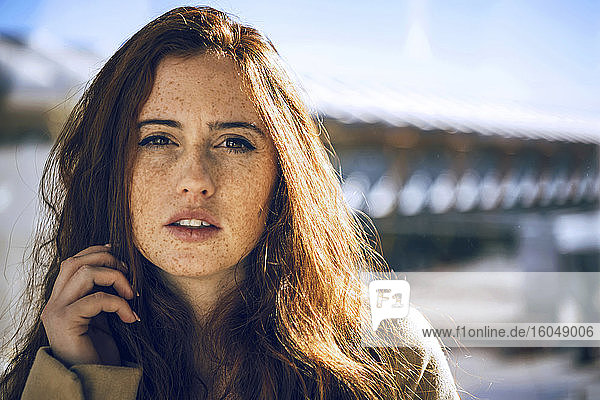 Confident woman with freckles on face during sunny day