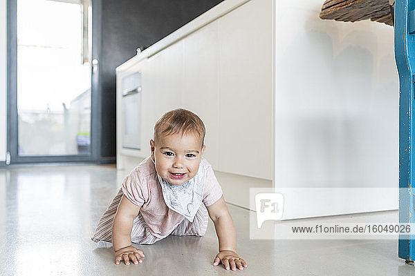 Süßes Baby Mädchen krabbeln auf dem Boden in der modernen Küche zu Hause
