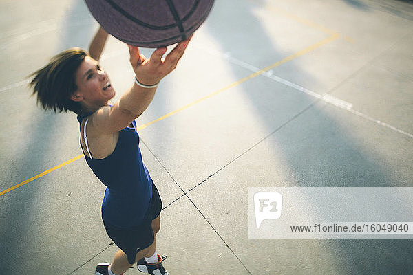Teenager-Mädchen springt beim Üben von Basketball auf dem Platz