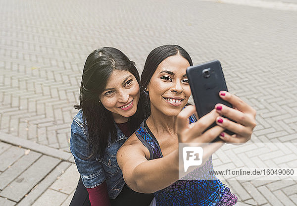 Smiling young woman taking selfie with friend