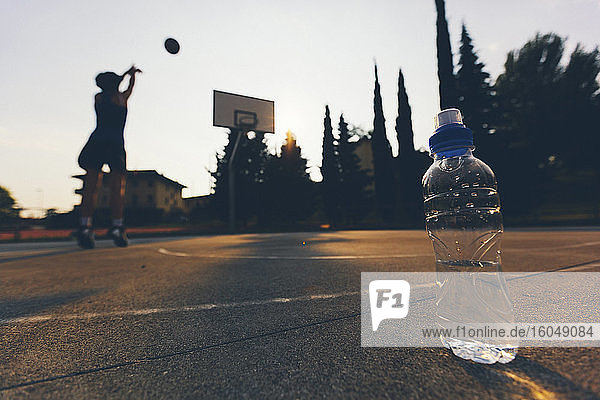 Nahaufnahme einer Wasserflasche in der Nähe einer Basketballspielerin  die auf dem Platz übt