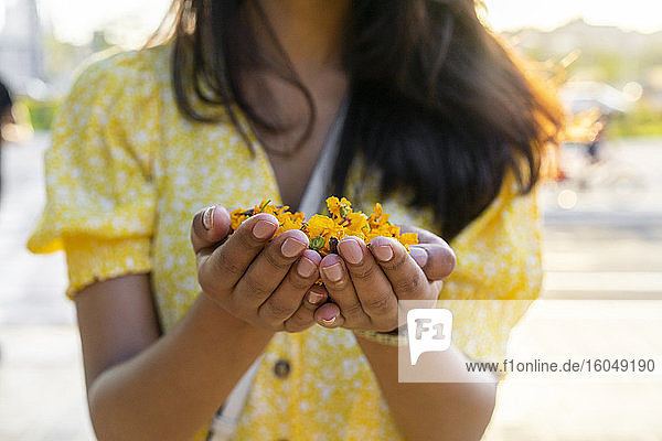 Junge Frau hält Blumen in den Händen in der Stadt im Sommer