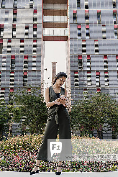 Weibliche Fachkraft schreibt in einen Notizblock  während sie vor einem modernen Gebäude steht