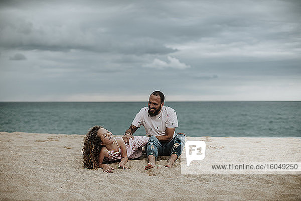 Vater spielt mit Tochter im Sand am Strand