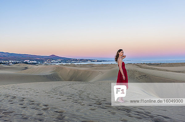 Frau in rotem Kleid bei Sonnenuntergang in den Dünen  Gran Canaria  Spanien