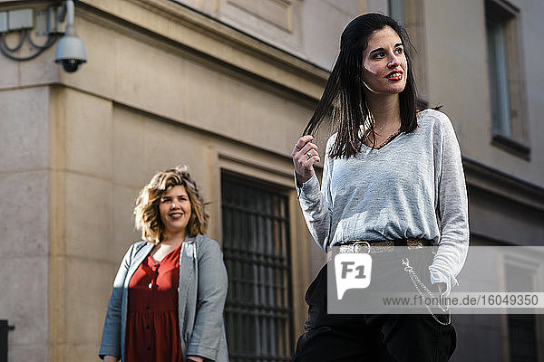 Frau schaut nachdenkliche Freundin an  während sie an einem Gebäude in der Stadt steht